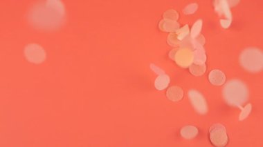Falling confetti on a pink background. Slow motion.