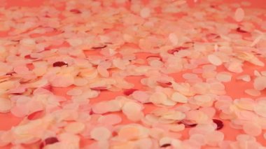 Falling confetti on a pink background. Slow motion.