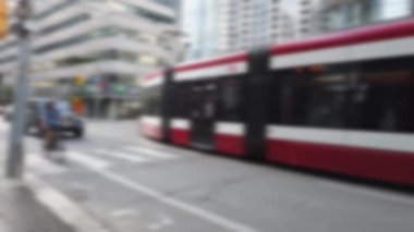 Modern trams, skyscrapers, streets and pedestrian crossing in downtown Toronto, Ontario, Canada. Out of focus.