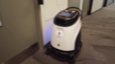 Robot vacuum cleaner cleans in the corridor of an office building. Toronto, Ontario, Canada. Out of focus.