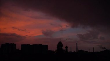 Şehrin üzerinde bulutlar ve yakıcı gün batımı.