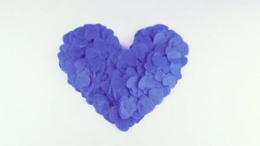 Heart-shaped confetti flies in the wind. Slow motion.