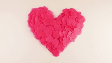 Heart-shaped confetti flies in the wind. Slow motion.
