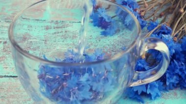 Brewing a tisanes from knapweeds flowers in a transparent cup.