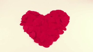 Heart-shaped confetti flies in the wind. Slow motion.