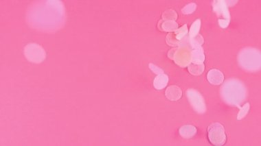Falling confetti on a pink background. Slow motion.