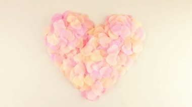 Heart-shaped confetti flies in the wind. Slow motion.