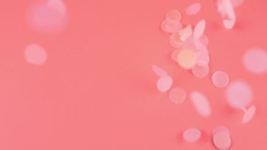Falling confetti on a pink background. Slow motion.