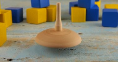 Peg oyuncağı ya da girdap oyuncak bloklarının arka planında eski bir tahta üzerinde döner..