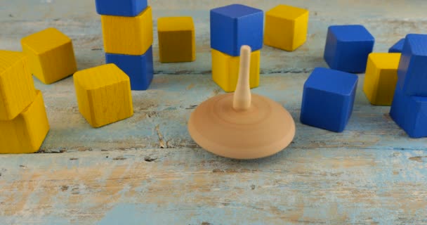 ペッグのおもちゃや旋回は 子供のおもちゃのブロックの背景にあるヴィンテージの木製ボードで回転します — ストック動画