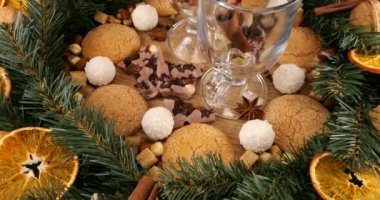 Sıcak şarap, kozalaklı dallardan, portakal dilimlerinden ve tatlılardan oluşan bir çelenk ile Noel temalı şenlik kompozisyonu.