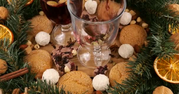 Ünnepi kompozíció a karácsony témájáról forralt borral, tűlevelű ágak koszorújával, narancsszeletekkel és édességekkel.