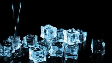 Siyah zemin üzerinde buz küplerinin üzerine bir su akıntısı düşer. Yavaş çekim.