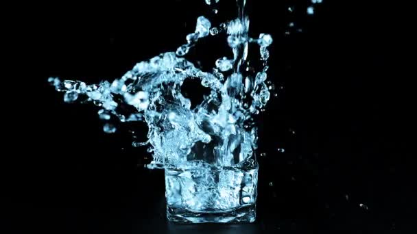 Реактивная Струя Воды Падает Стеклянный Контейнер Черном Фоне Создает Всплеск — стоковое видео