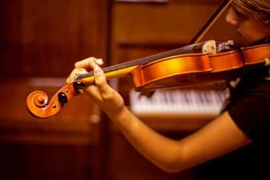 Genç kemancı, sırtı piyanonun yanında yatay olarak kemanla müzik çalar.