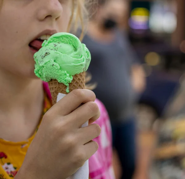 licking a delicious ball of mint ice cream outdoors, horizontal