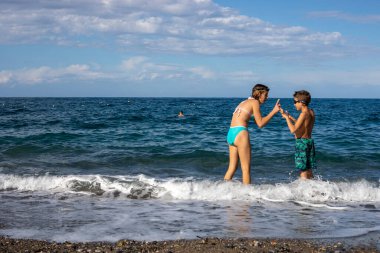 Açık denizde yüzen mutlu çocuklar, aile tatili, yatay