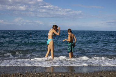 Açık denizde yüzen mutlu çocuklar, aile tatili, yatay