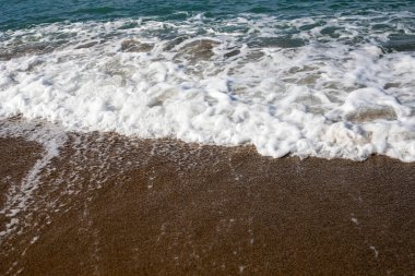 Deniz arka planında köpüklü sörf kumlu plaj manzaralı, yatay