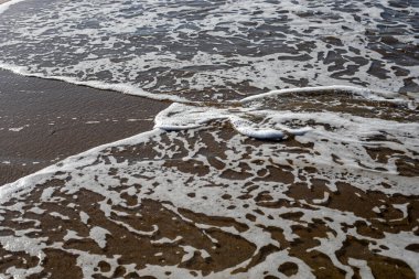 Deniz arka planında köpüklü sörf kumlu plaj manzaralı, yatay