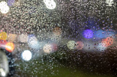 Yağmurda trafik sıkışıklığı sırasında arabanın ön camında bulanık bir arkaplan var.