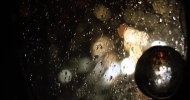 Yağmurda trafik sıkışıklığı sırasında parlak ışıkları olan bir arabanın sağ yan aynasındaki bulanık arka plan.,