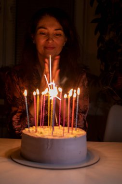 Mutlu kız doğum günü pastasındaki mumları üflemeden önce ellerini çırpıyor.,