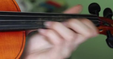 Genç kemancı sol eliyle keman çalıyor.