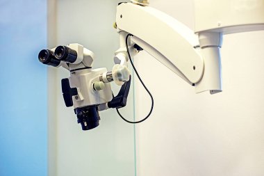 Diş mikroskobu ve diş muayenehanesindeki dürbünleri hafif arka planda çalıştırmak, modern tıp teknolojileri