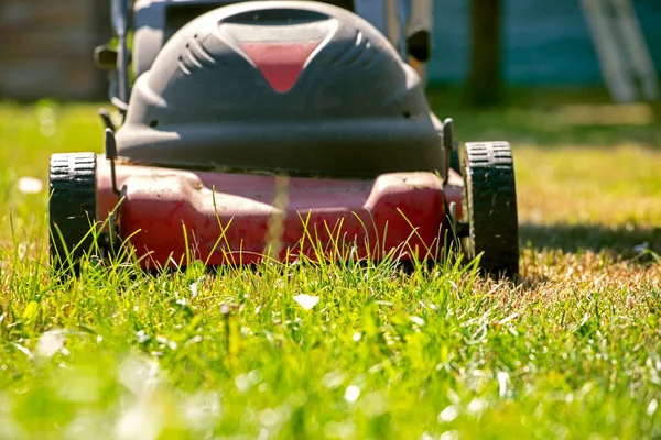 electric lawn mower on a sunny day on a green lawn in front, against the su