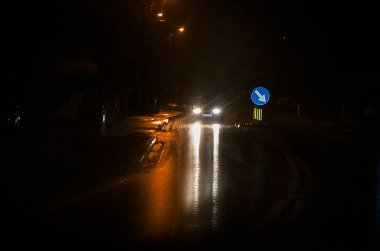 Gece, yağmurlu ve kötü havada yol üzerindeki bulanık mavi tabela dönüş sinyali.