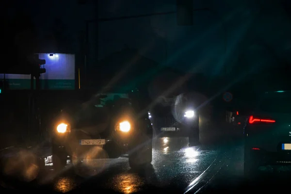 blurry glare from headlights on windshield in bad rainy weather at night at traffic ligh