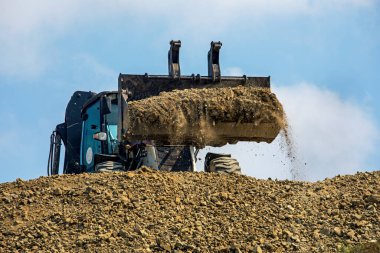large bucket with escalator soil frontally on a sunny hot day against the sky. Global construction.