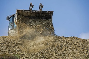 escalator bucket pours out clay and stone soil in a quarry. Global construction.