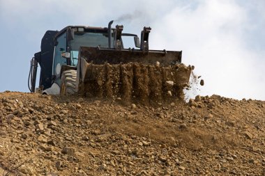 huge bucket of an escalator pours out clay soil. Global construction. Mining.