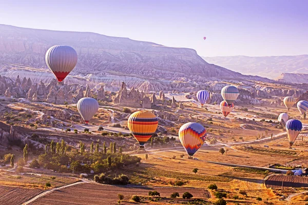 many colorful balloons land on the goreme hills in Cappadocia in the early morning. Entertainment