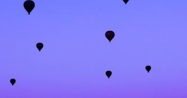 dark silhouettes of flying balloons in the blue clear sky in the vicinity of Cappadocia in the early morning. Leisure