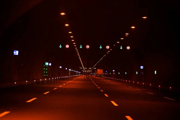 Night road tunnel illuminated by headlights. Traffic