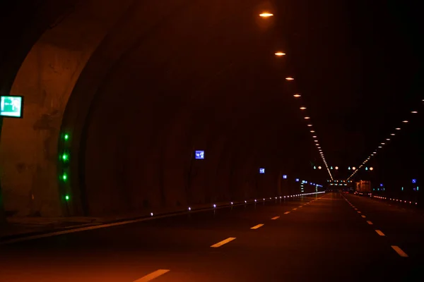 Night road tunnel illuminated by headlights. Traffic