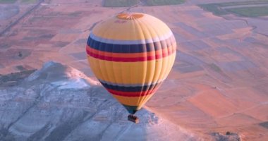  huge yellow hot air balloon descends in the Cappadocia Valley near Goreme in the early morning