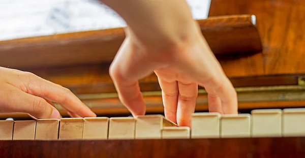 happily practicing with two hands on a piano with ivory keys a piece of music, bottom view. music lesson