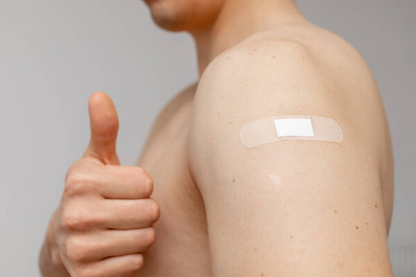 Man with patch on the shoulder showing thumbs up