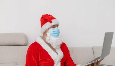 Bilgisayarlı Noel Baba gibi giyinmiş bir adam.