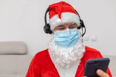 Noel Baba gibi giyinmiş kulaklık takan bir adam.