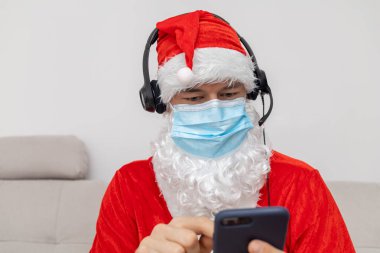 Noel Baba gibi giyinmiş kulaklık takan bir adam.