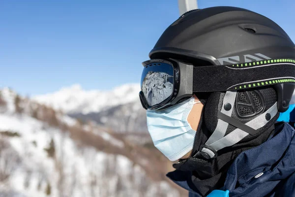 Лыжный курорт человек на подъемнике в шлеме и медицинской маске — стоковое фото