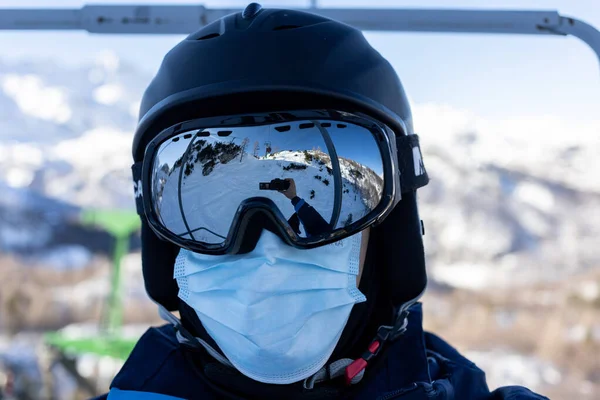 Station de ski homme sur télésiège en casque et masque médical — Photo