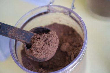 Plastik bir kavanozdan çıkarılmış kaşıktaki kakao tozu..