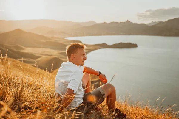 Młody Człowiek Siedzi Szczycie Góry Trawie Ciesząc Się Widokiem Wybrzeże — Zdjęcie stockowe
