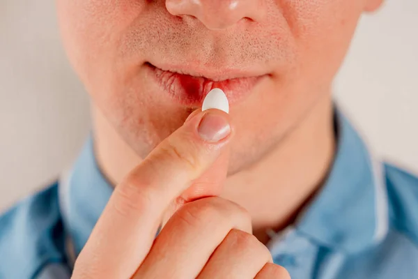 A young aucasian man takes a pill. Man making medicine at home, closeup